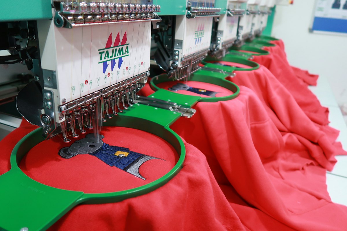 Embroidery machine stitching a logo onto shirts